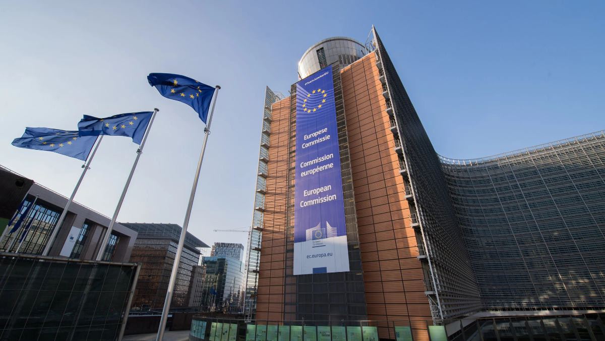 European Commission building with EU flags waving in front under clear sky